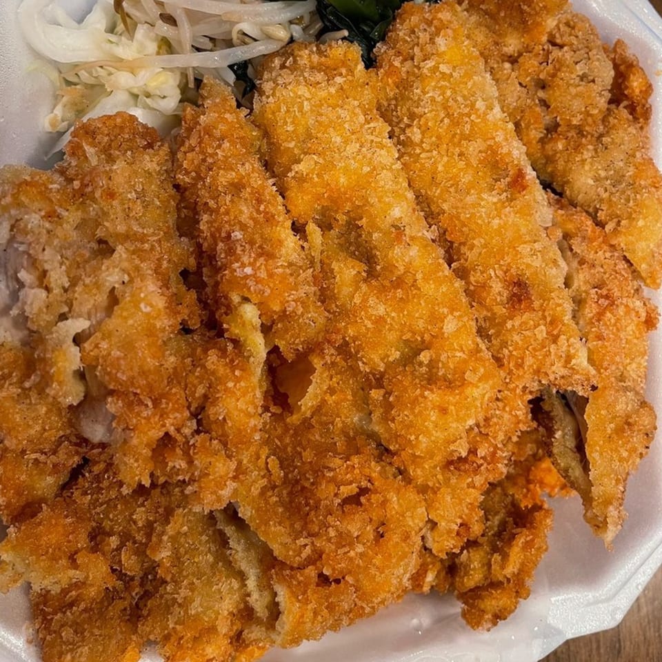 Crispy golden-brown fried chicken cutlets with a side of bean sprouts and green vegetables.