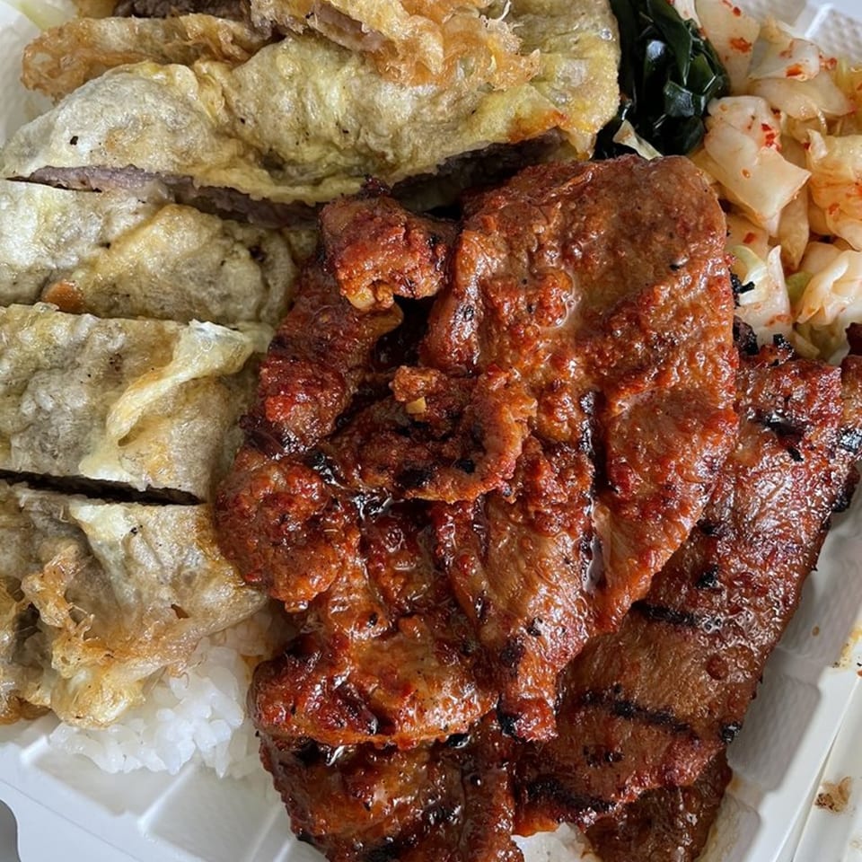 Close-up of Kim Chee Restaurant's Korean BBQ plate with grilled meat, fried dumplings, rice, and kimchi.